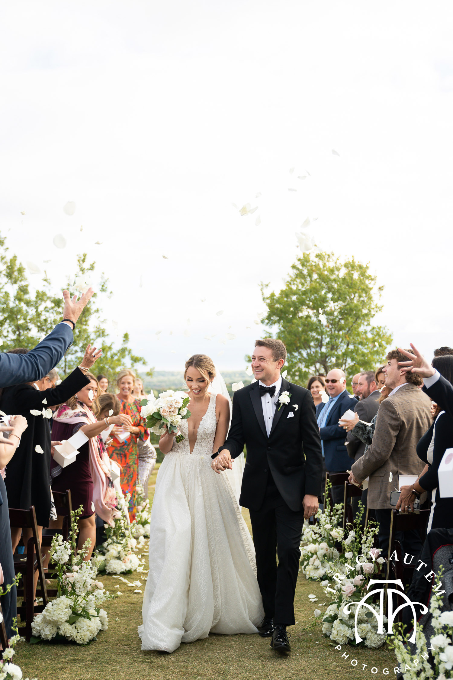 Outdoor ceremony recessional with couple walking and flower petals being thrown