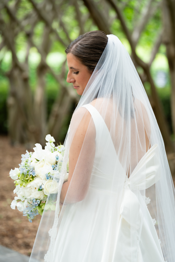 Hannah smiling in her gown with the Dallas Arboretum gardens behind her