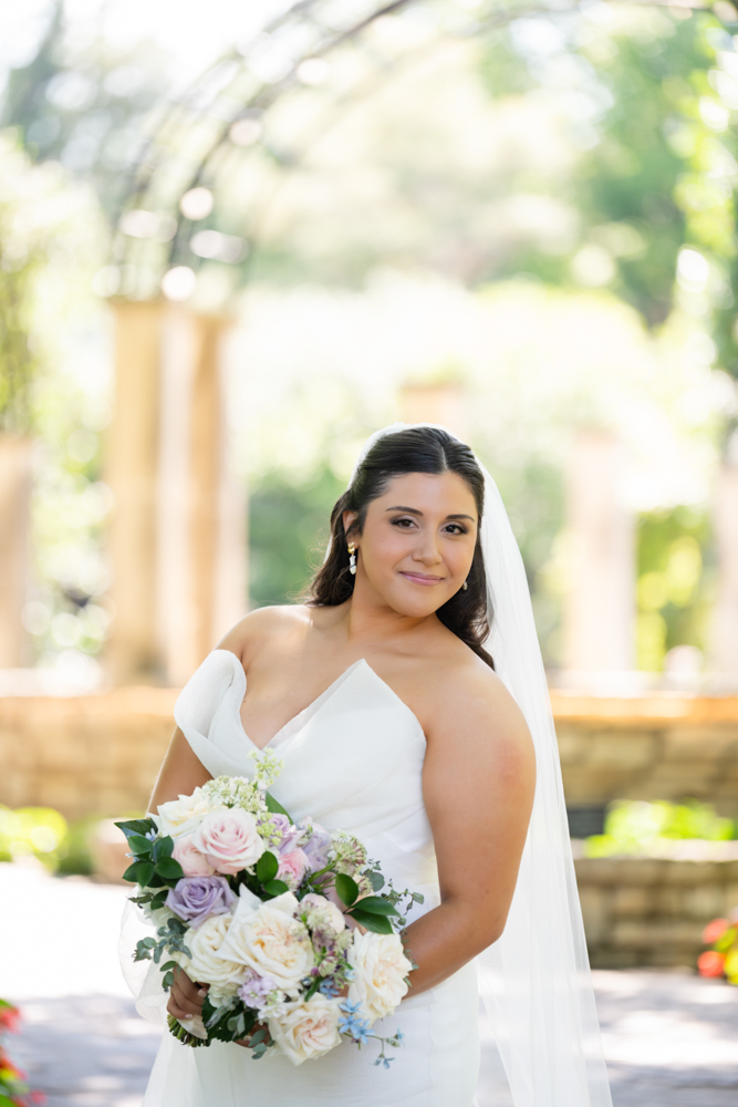 Caroline smiling in her gown with garden blooms behind her
