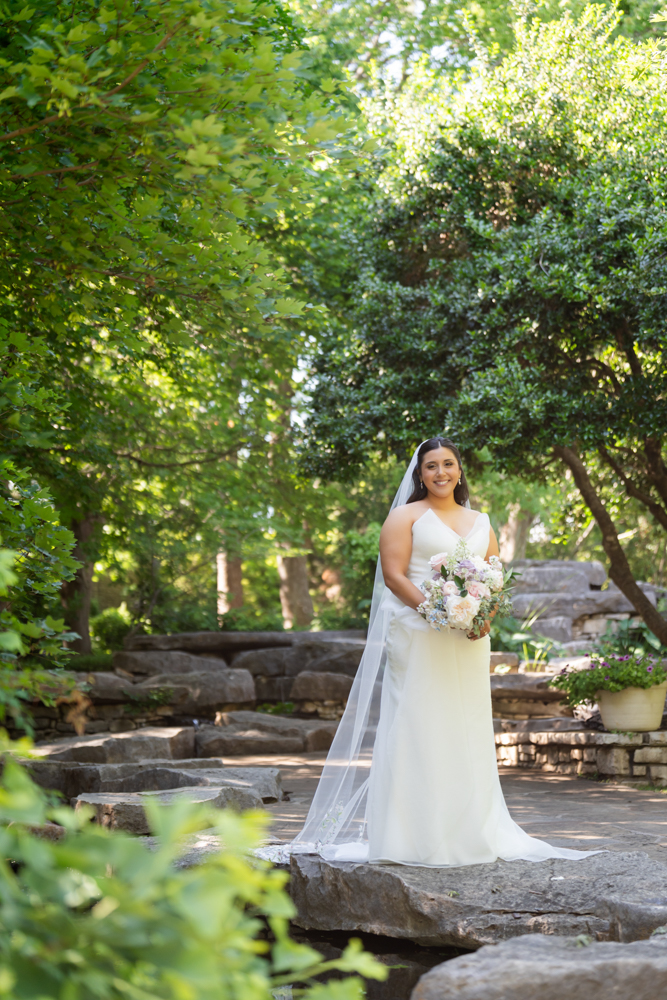 Caroline smiling in her gown with garden blooms behind her