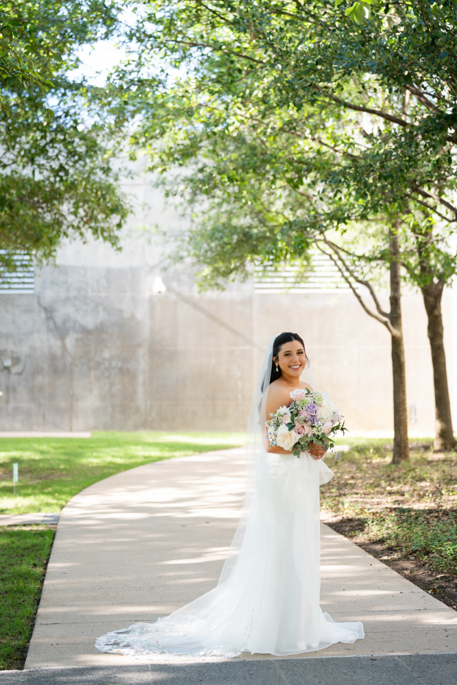 Caroline walking through the greenery in her wedding dress