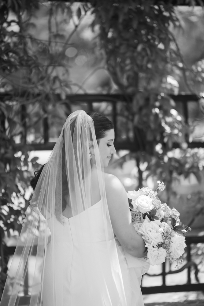 Caroline walking through the greenery in her wedding dress