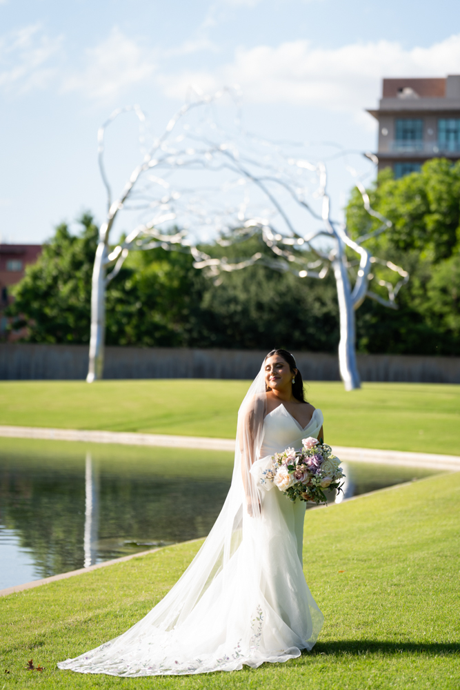 Caroline walking through the greenery in her wedding dress