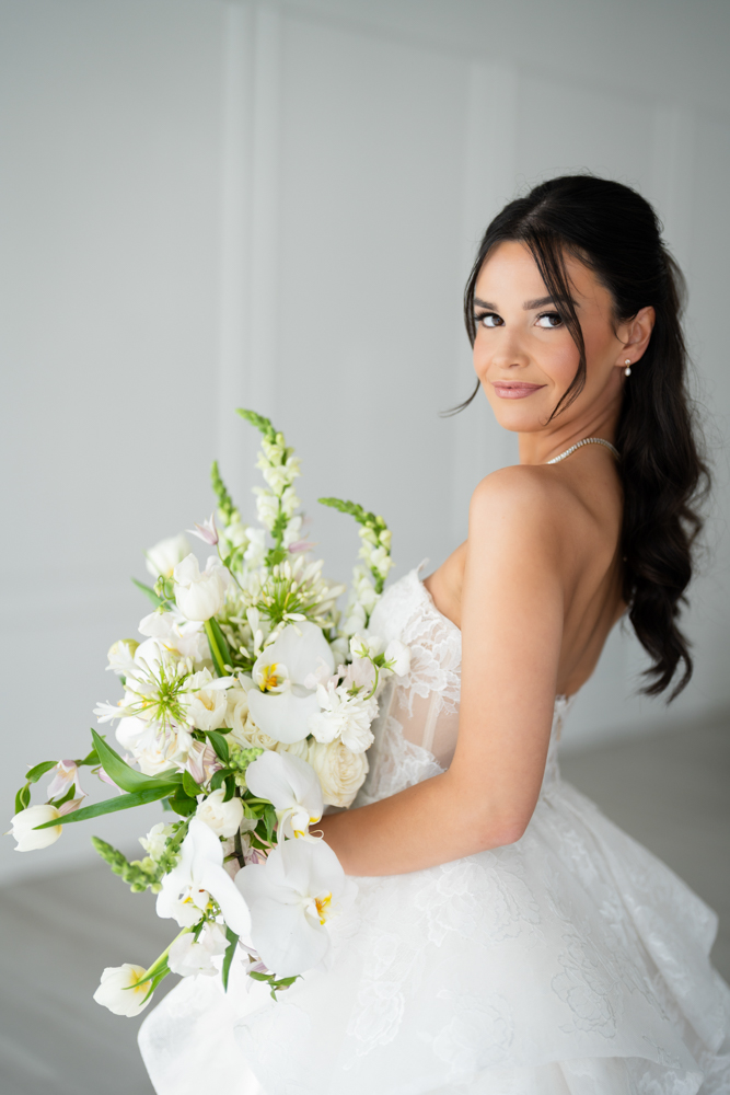 Hannah holding her bouquet as soft light falls across her gown